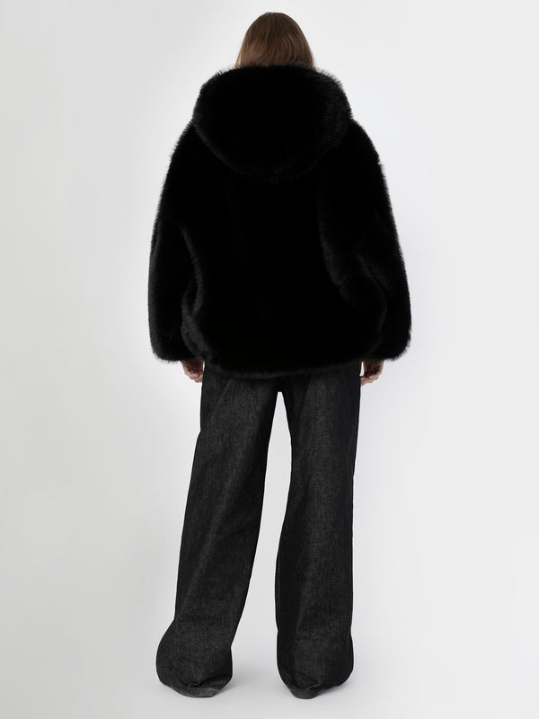 A model wearing a black faux fur oversized hoodie with a hood, paired with wide-leg dark denim pants, showcasing MEOTINE's style.