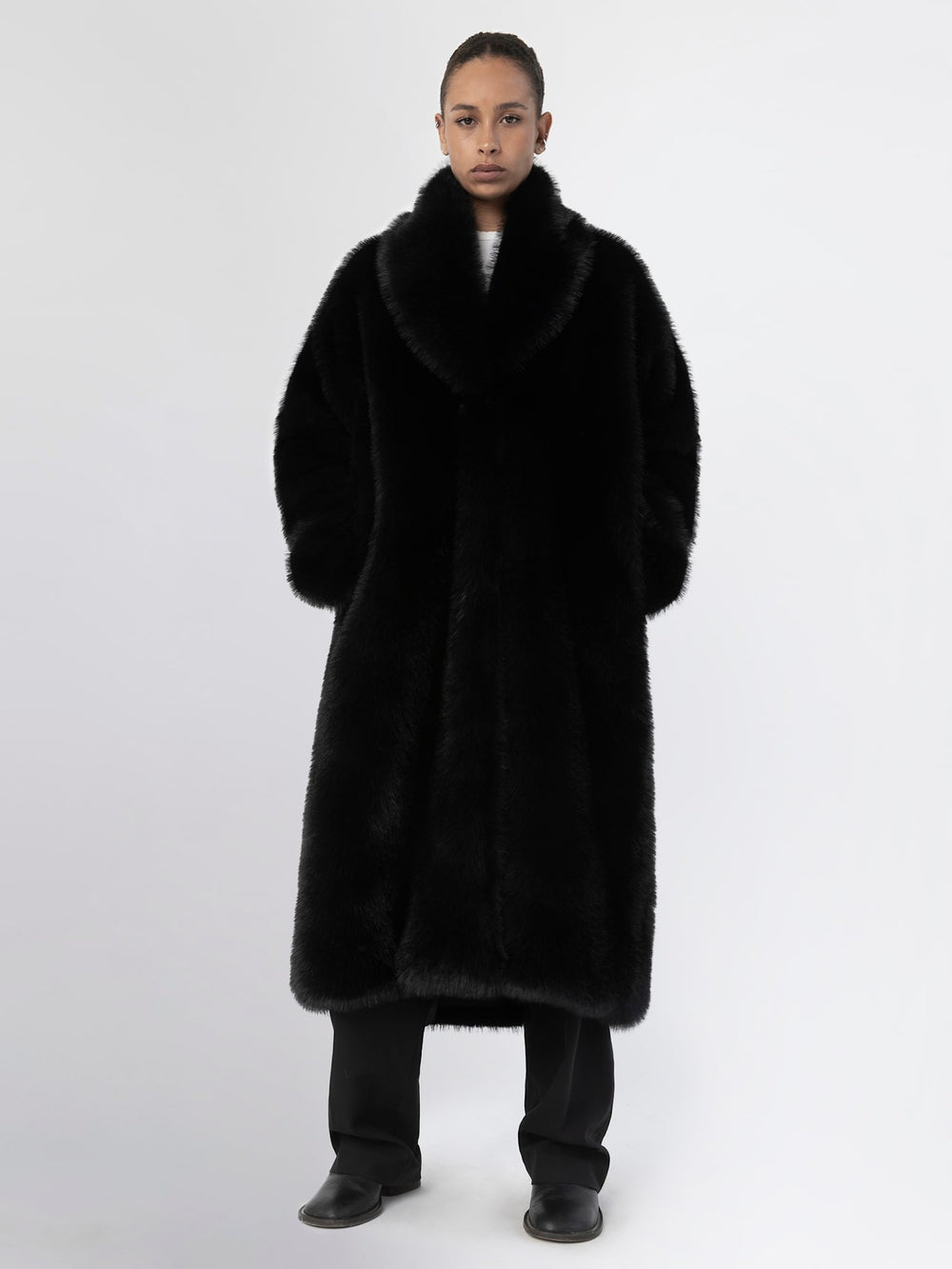 A model wears a luxurious black faux fur coat by MEOTINE, featuring a wide collar and a relaxed fit, perfect for stylish warmth.