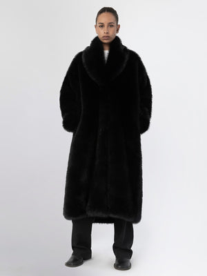 A model wears a luxurious black faux fur coat by MEOTINE, featuring a wide collar and a relaxed fit, perfect for stylish warmth.