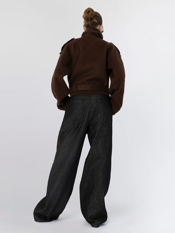 A model wearing a brown oversized jacket and wide-leg black pants, showcasing a stylish and modern look by MEOTINE.