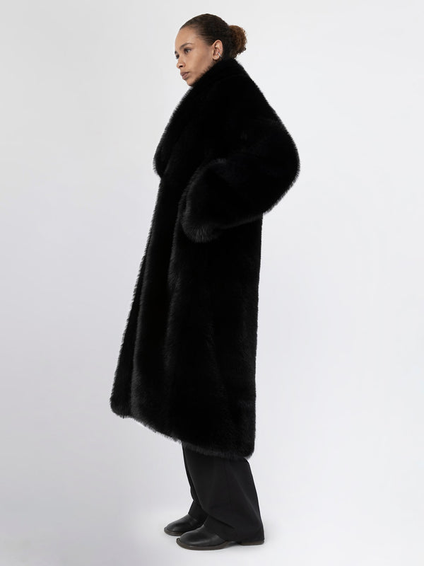 A model wearing a luxurious black faux fur coat by MEOTINE, showcasing a stylish and elegant silhouette against a plain background.