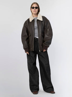 A model showcases a stylish brown leather jacket with a shearling collar, paired with oversized black pants, embodying MEOTINE's chic aesthetic.