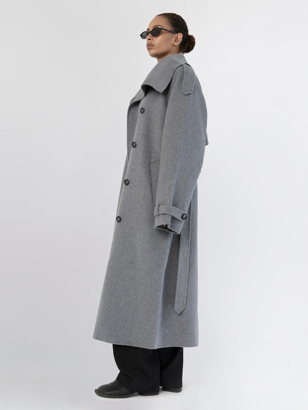 A model showcases a stylish gray oversized coat with a dramatic collar, paired with sleek black attire and sunglasses, by MEOTINE.