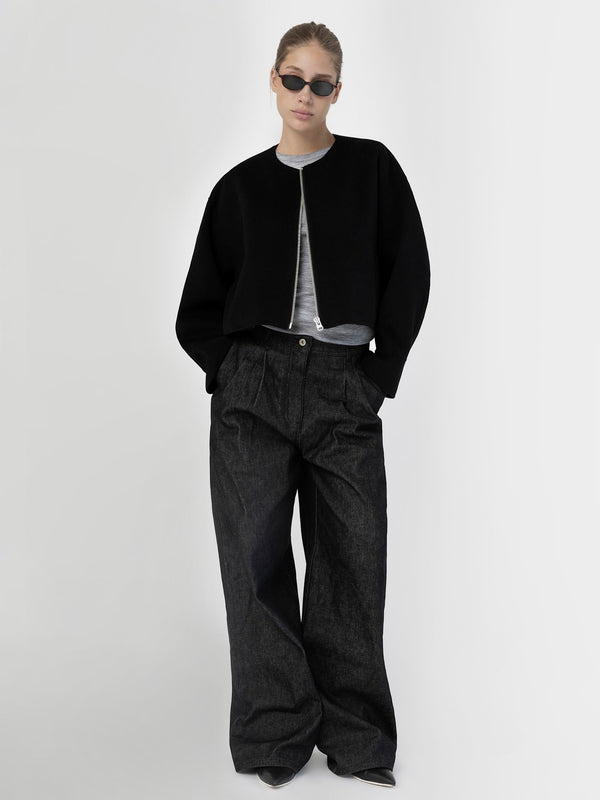 A model wears a cropped black jacket over a gray top, paired with wide-leg dark jeans, showcasing MEOTINE's stylish design.