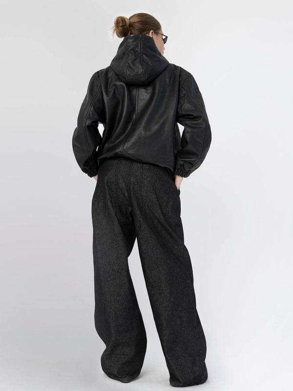 Stylish black leather jacket with a hood paired with loose-fitting dark denim pants, showcasing a modern, casual look by MEOTINE.
