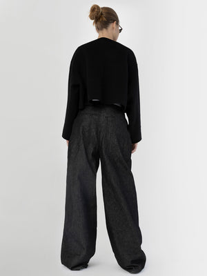 A model wearing a cropped black sweater and wide-leg dark denim pants from MEOTINE, showcasing a stylish back view.