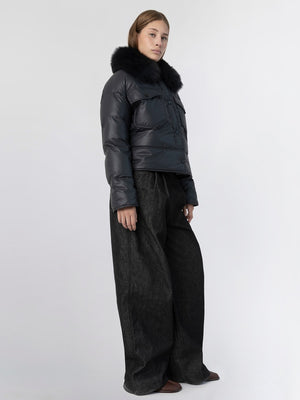 A model showcases a stylish black puffer jacket with a fur collar, paired with wide-leg dark pants, representing MEOTINE's chic aesthetic.