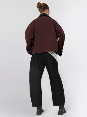 A model wearing a maroon oversized jacket paired with black wide-leg pants, showcasing a stylish and modern look by MEOTINE.