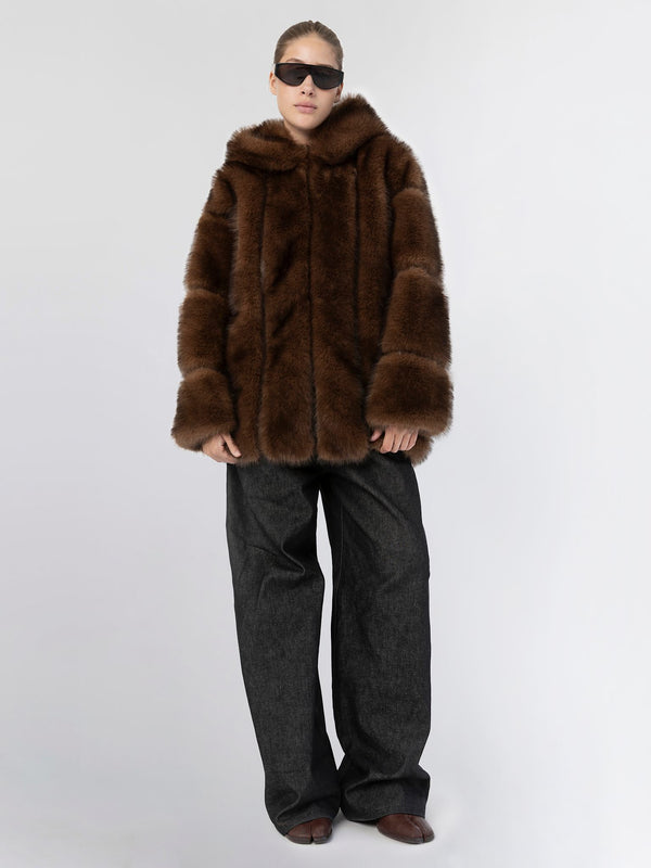 A model wears a luxurious brown faux fur coat with a hood, paired with loose dark trousers and stylish sunglasses, showcasing MEOTINE's elegance.
