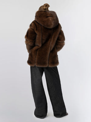 Luxurious brown fur coat with a hood, paired with wide-leg black pants, showcasing a stylish and cozy look by MEOTINE.