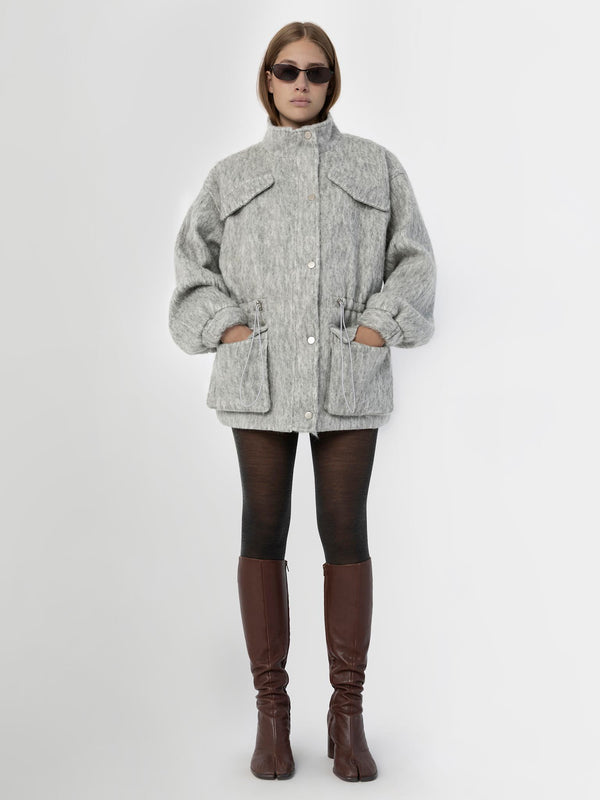 A model wears a cozy gray MEOTINE jacket with a high collar, paired with black leggings and stylish brown knee-high boots.
