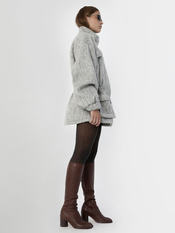 A model showcases a stylish gray oversized jacket paired with black leggings and brown knee-high boots, embodying MEOTINE's chic aesthetic.
