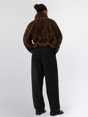 Cozy brown faux fur jacket paired with loose black trousers, showcasing a relaxed and stylish look by MEOTINE.