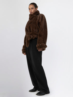 A model wears a cozy brown faux fur jacket with a belted waist, paired with wide-leg black trousers, showcasing MEOTINE's style.