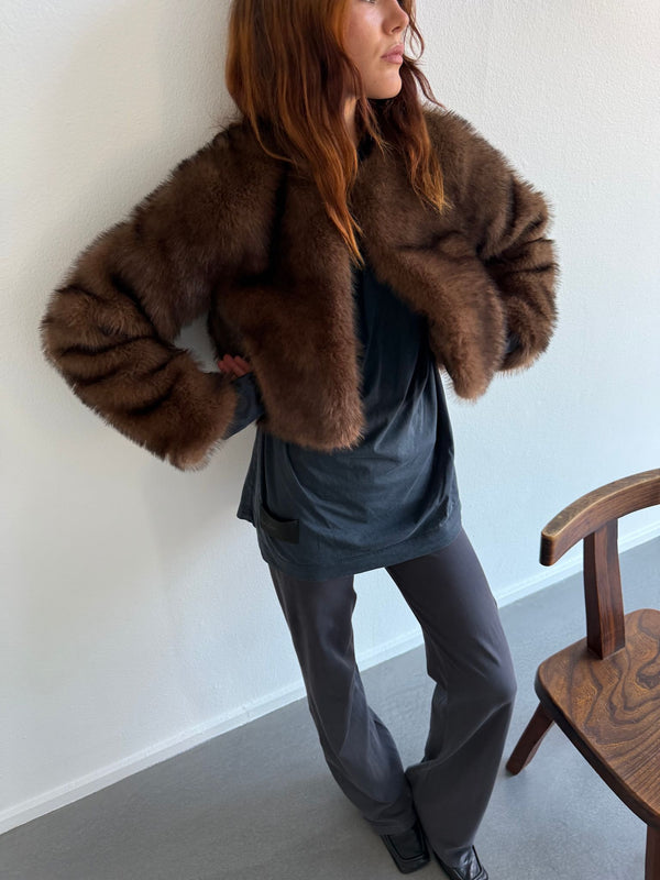A model showcases a stylish brown fur jacket by MEOTINE, paired with a casual top and sleek pants, exuding elegance and warmth.