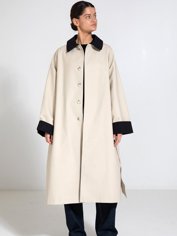 A model showcases a stylish beige coat with a black collar and cuffs, embodying MEOTINE's modern elegance.