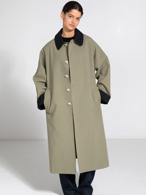 A model wears a stylish olive green coat with a black collar and pockets, showcasing MEOTINE's modern design.
