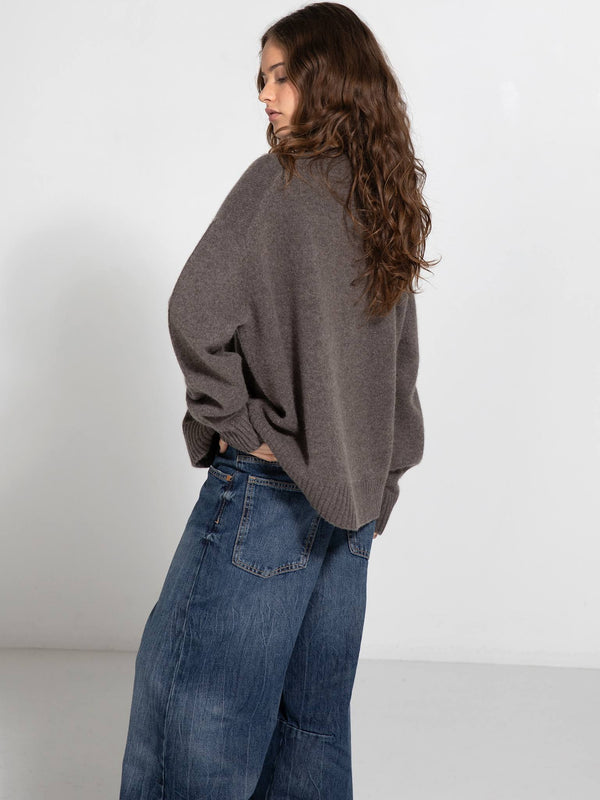 A model showcases a cozy, oversized gray sweater paired with loose denim jeans, embodying a relaxed style by MEOTINE.