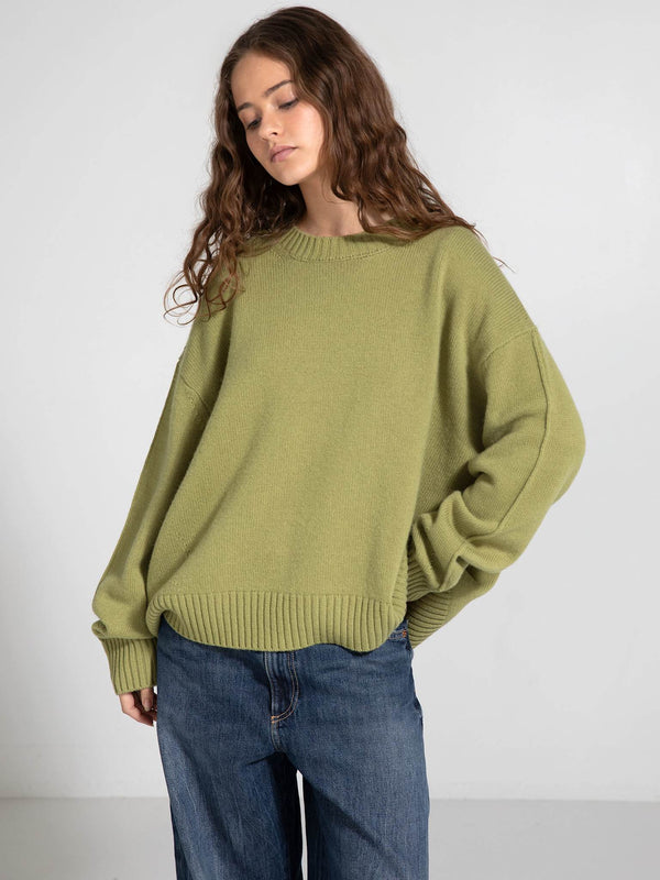 Oversized green sweater with a relaxed fit, paired with loose denim jeans, showcasing a casual style by MEOTINE.