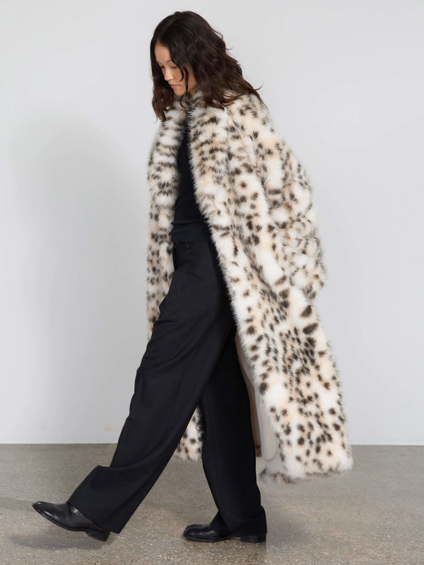 A model walks gracefully in a stylish MEOTINE faux fur coat with a spotted pattern, paired with black trousers and boots.