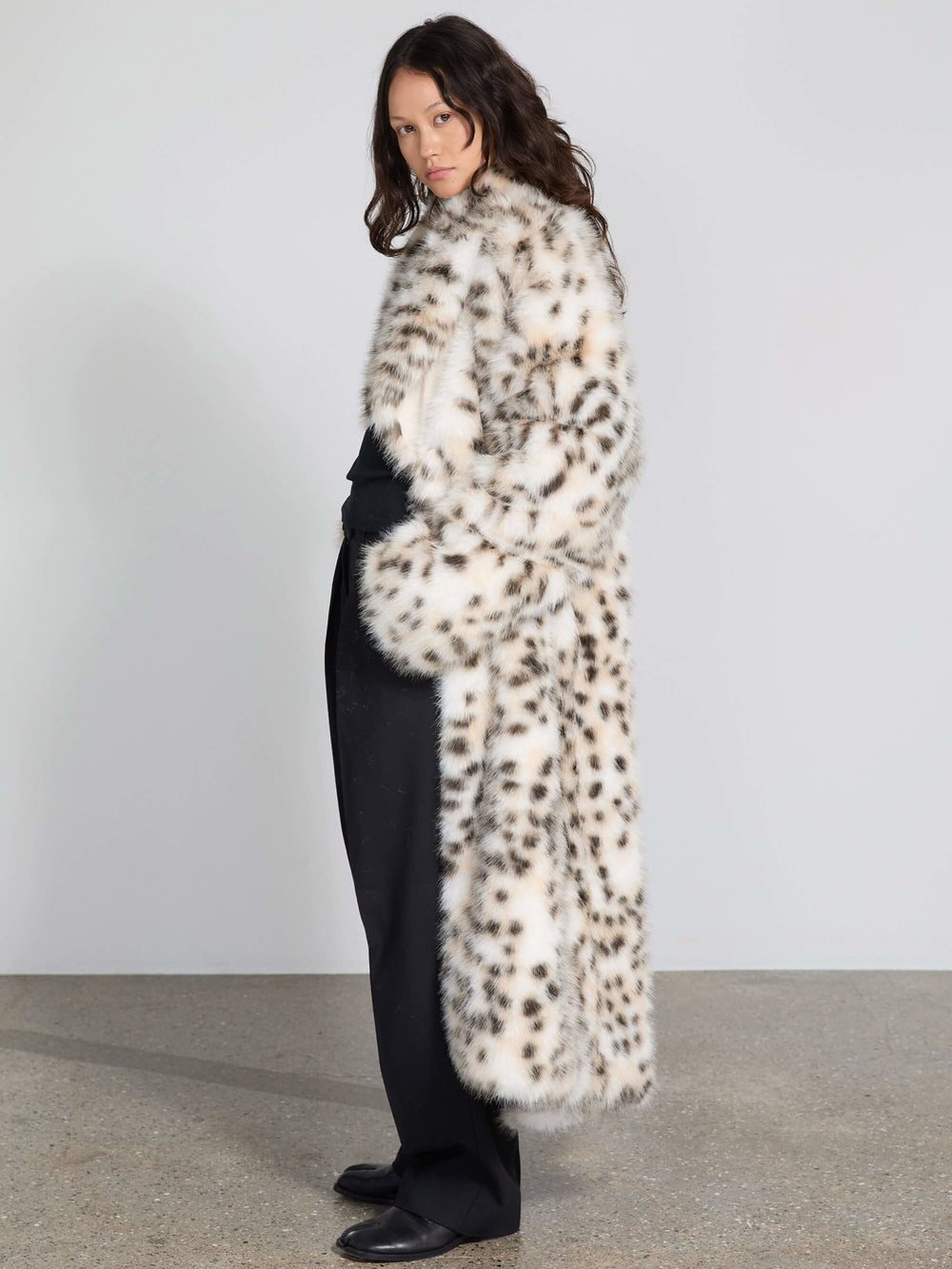 A model showcases a stylish MEOTINE faux fur coat with a leopard print, paired with a black top and wide-leg trousers.