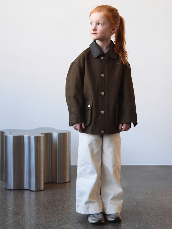 A child stands in a stylish brown jacket with a collar, paired with white wide-leg pants, showcasing MEOTINE's trendy design.