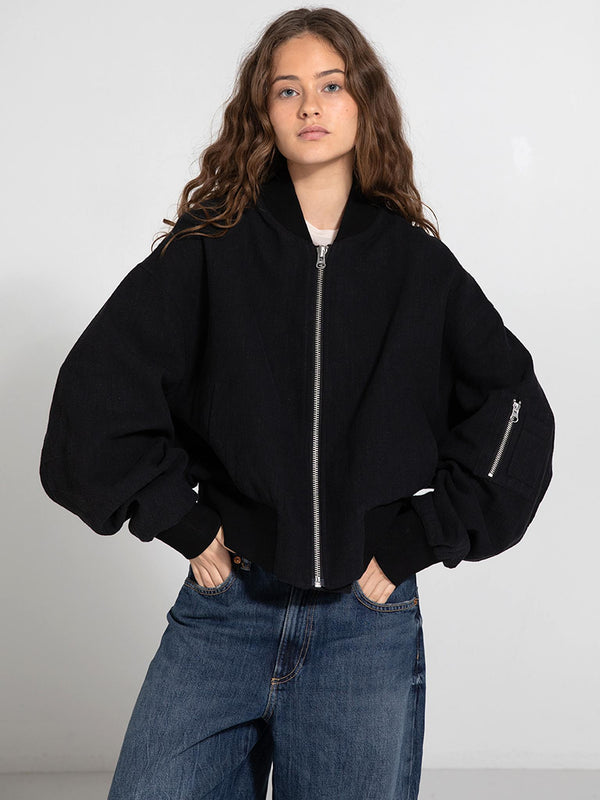 A model poses in a stylish black cropped jacket with oversized sleeves, paired with relaxed denim jeans, showcasing MEOTINE's trendy design.