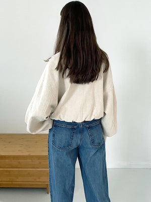 Casual back view of a woman wearing a light beige oversized shirt and high-waisted blue jeans, showcasing MEOTINE's relaxed style.