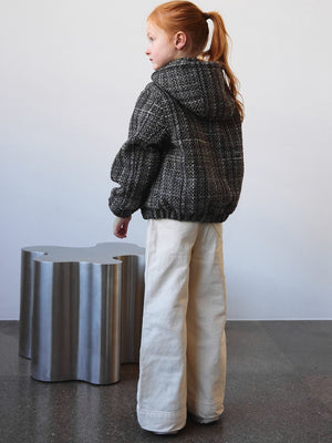 A girl in a stylish black and white textured jacket with a hood, paired with cream wide-leg pants, showcasing MEOTINE's modern design.