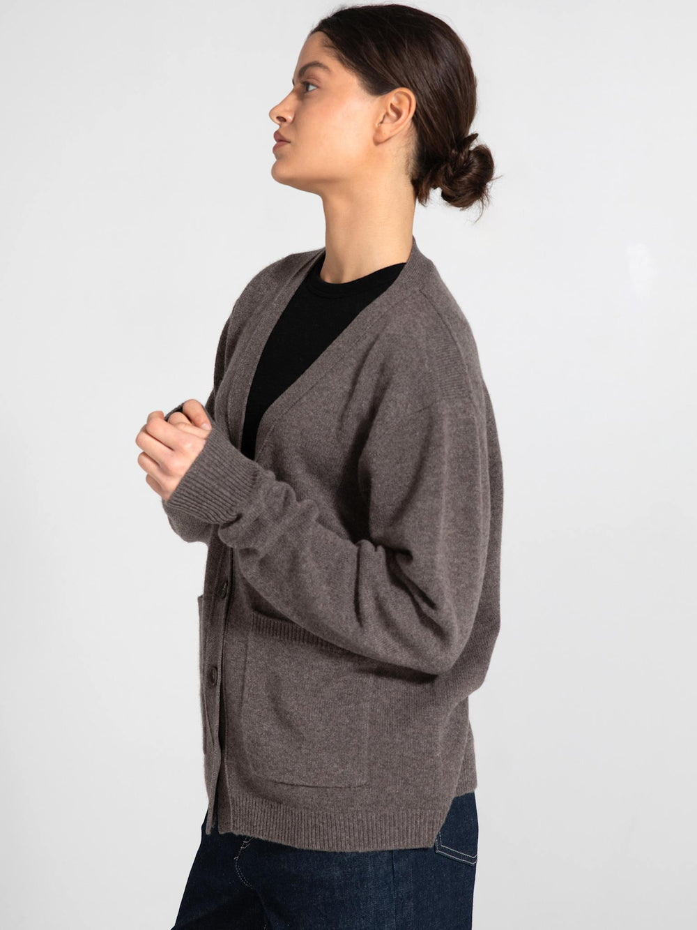 A model wears a cozy, brown cardigan with a V-neck and button closure, featuring two front pockets, by MEOTINE.