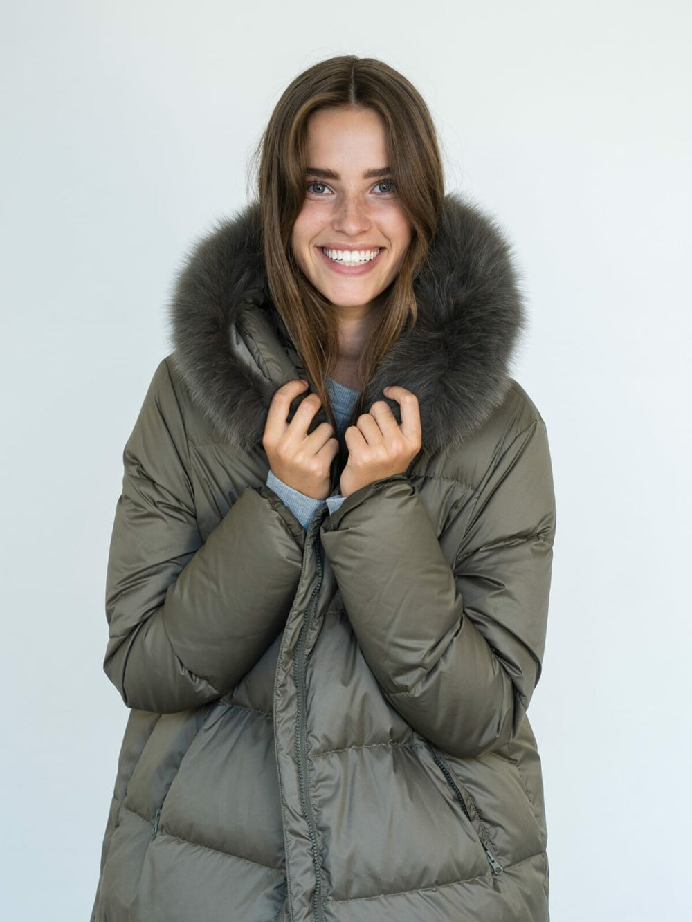 Stylish long olive green puffer coat with a fur-lined hood, perfect for winter, by MEOTINE. Model stands against a plain background.