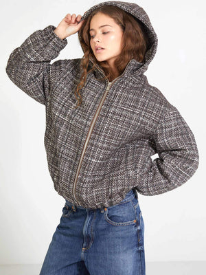 Stylish woman in a cozy, oversized plaid jacket with a hood, paired with denim jeans, showcasing MEOTINE's chic design.
