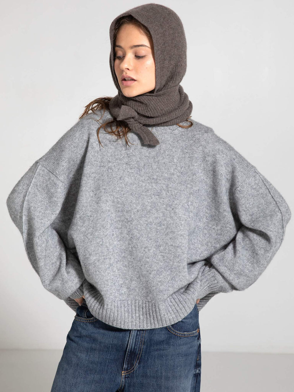 A model showcases a cozy gray sweater paired with a warm brown MEOTINE hood, highlighting a stylish and comfortable look.