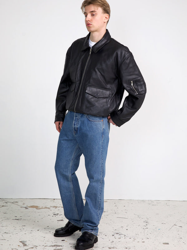 A model wearing a black leather bomber jacket paired with blue jeans and black shoes, showcasing MEOTINE's stylish outerwear.