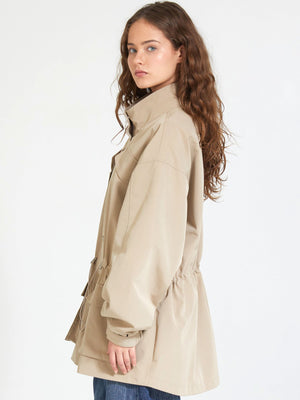 A model wearing a beige MEOTINE jacket with a cinched waist, showcasing a relaxed fit and stylish design.