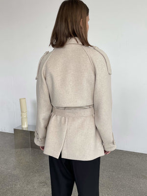 A model showcases a stylish beige coat with a belted waist and shoulder details, perfect for a chic look by MEOTINE.