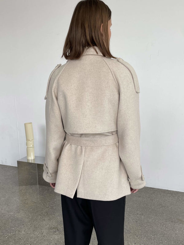 A model showcases a stylish beige coat with a belted waist and shoulder details, perfect for a chic look by MEOTINE.