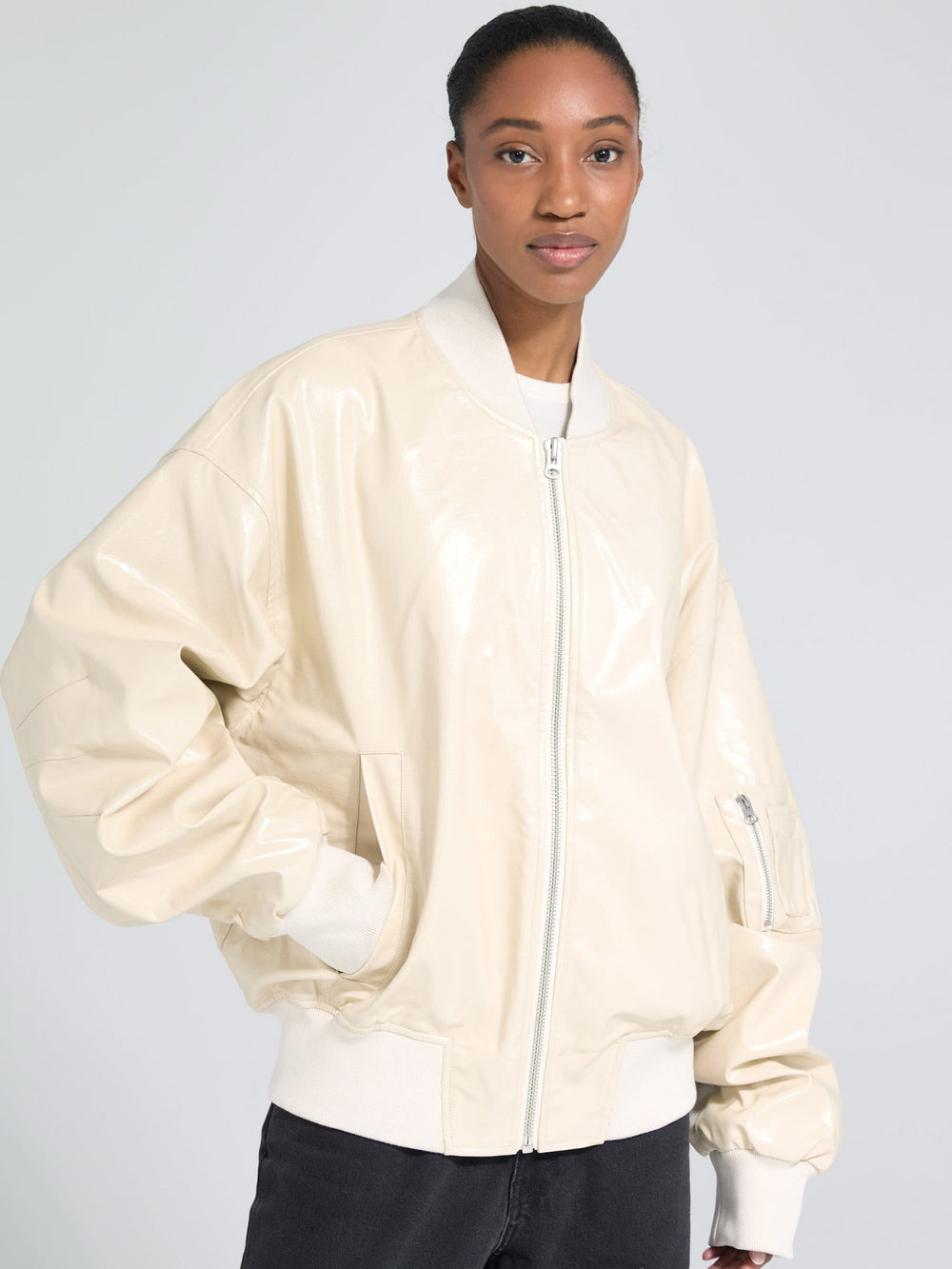 A model wears a glossy beige bomber jacket with oversized sleeves, showcasing a stylish and modern look by MEOTINE.