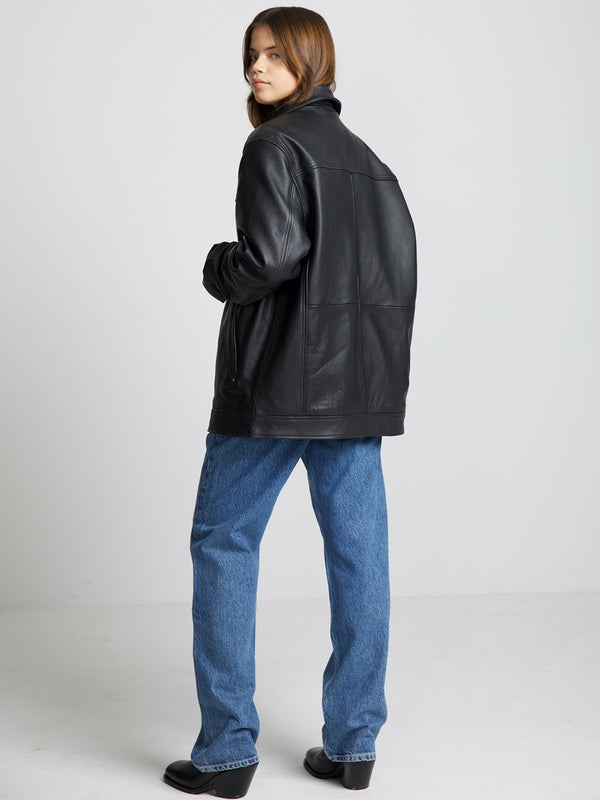 A model wearing a black leather jacket from MEOTINE, paired with blue jeans, showcasing a stylish and modern look from the back.