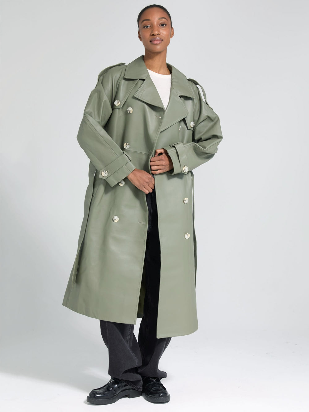 A model showcases a stylish oversized green trench coat by MEOTINE, paired with a simple white top and black trousers.