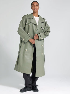 A model showcases a stylish oversized green trench coat by MEOTINE, paired with a simple white top and black trousers.