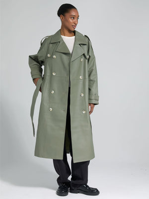 A model showcases a stylish green trench coat by MEOTINE, featuring a double-breasted design and a relaxed fit, paired with black pants.
