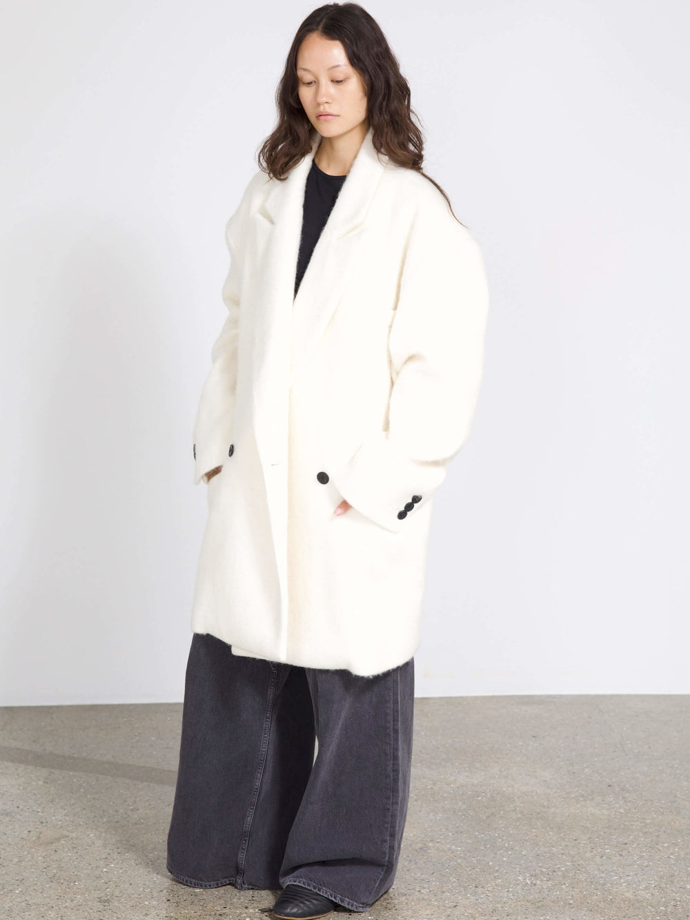 A model wearing a cozy white oversized coat paired with wide-leg dark jeans, showcasing MEOTINE's stylish winter collection.