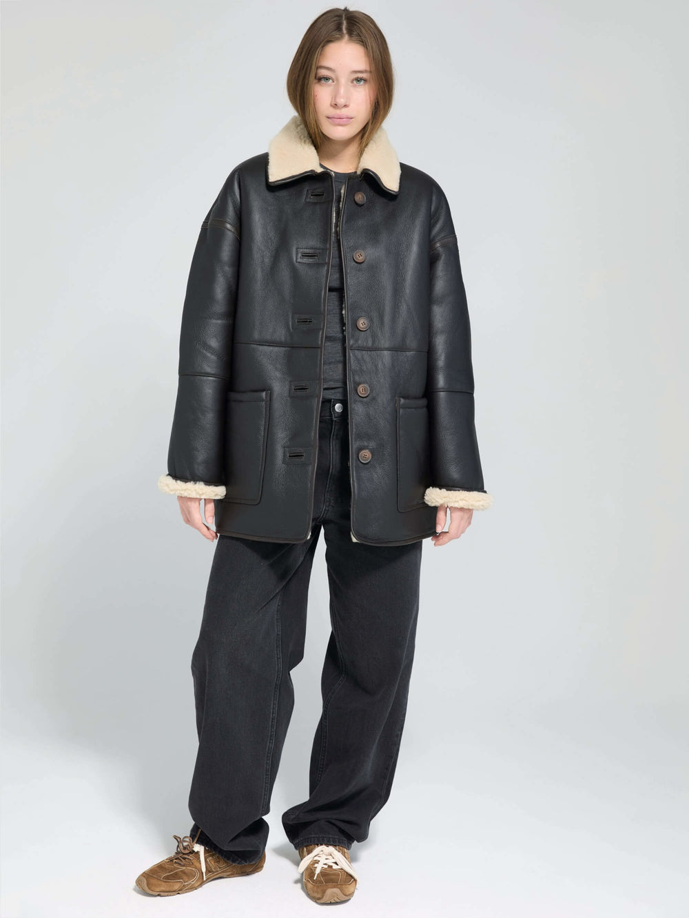 A model wears a stylish black MEOTINE jacket with a cozy beige fur collar, showcasing a chic and modern look.