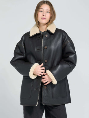 A model wears a stylish black MEOTINE jacket with a cozy beige fur collar, showcasing a chic and modern look.