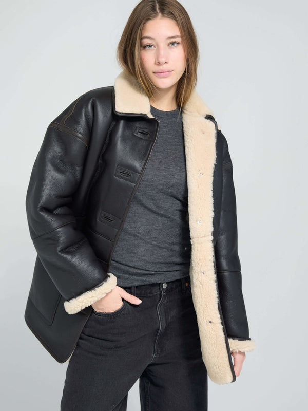 Stylish black leather jacket with a cozy cream shearling collar, perfect for a chic winter look by MEOTINE.
