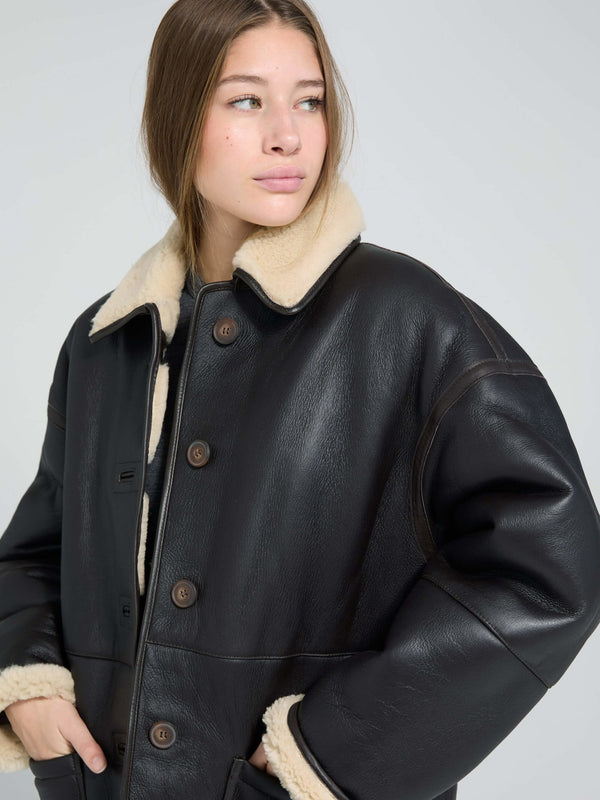 A model wears a stylish black leather jacket with a cozy cream shearling collar, showcasing MEOTINE's chic design.