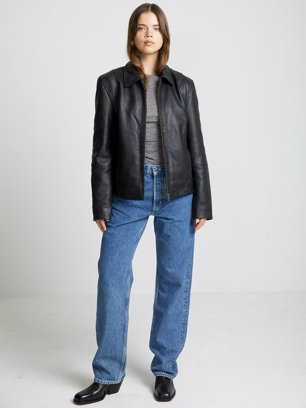 A model wears a stylish black leather jacket paired with light blue jeans, showcasing a modern look by MEOTINE.