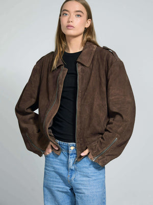 Brown oversized jacket with a relaxed fit, featuring a zip closure and side pockets, styled with a black top and blue jeans. MEOTINE.