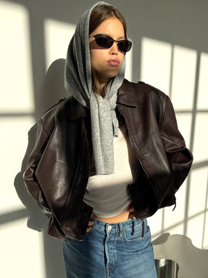 A model showcases a stylish brown leather jacket paired with a gray hoodie and sunglasses, embodying a chic urban look by MEOTINE.